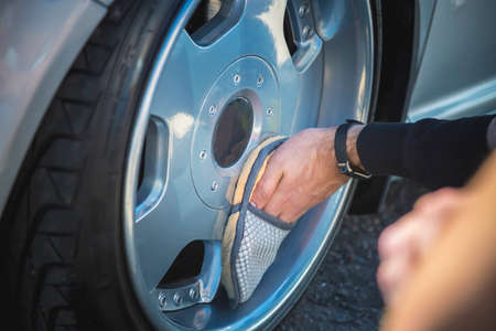 A man cleans the wheels of his car. Dropped silver car on air suspension.の写真素材