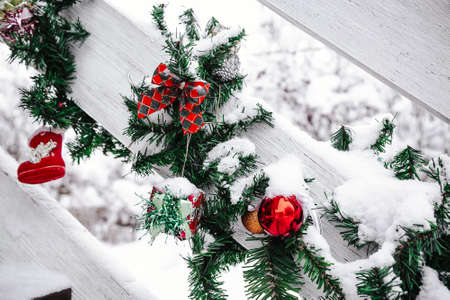 Christmas and New Year decorations on the street. On wooden handrails. Christmas tree and balls, toys, bows and small gifts. In the snow.の写真素材