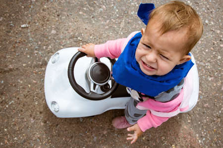 A small child is riding a toy car. and very unhappy. View from above. A special car that needs to be kicked. Tolokar.の写真素材