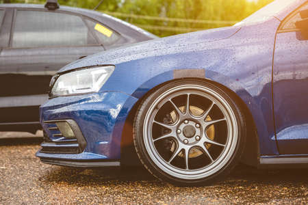 Blue modern car with light alloy wheels parked on the street. It was raining, drops on the body. Tuning of german vehicleの写真素材