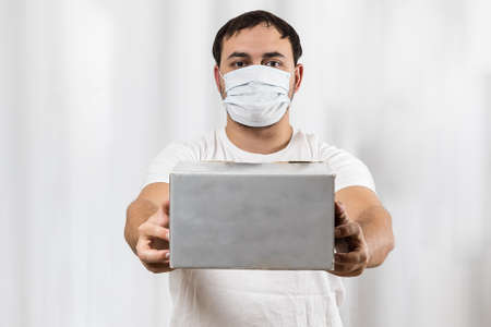 Contactless delivery. Delivery man wearing a medical mask. He brought the box. Mockup.