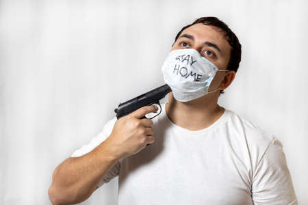 Depressed state. Suicide desire. The horror of isolation. The man in the mask. Handcuffed. With a pistol. Medical quarantine. Mental disorder. On a white background. Prisonerの写真素材