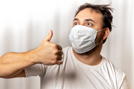 A man in a medical mask is playing a console. in the hands of a joystick. quarantine and isolation.の写真素材