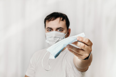 A man in a medical mask is playing a console. in the hands of a joystick. quarantine and isolation.の写真素材