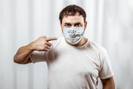 A man in panic looks at the phone and reads the news of the epidemic. In a protective medical maskの写真素材