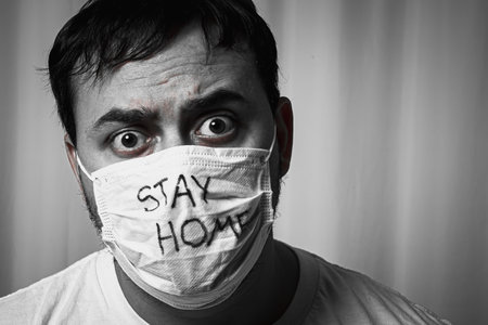 A man in panic looks at the phone and reads the news of the epidemic. In a protective medical maskの写真素材