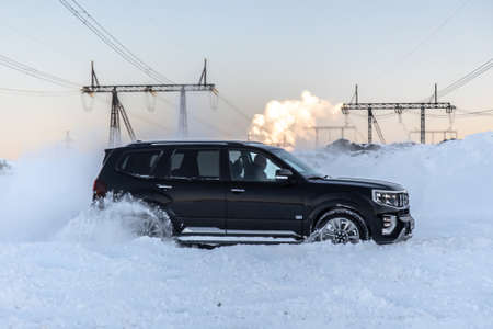 Moscow, Russia - February 15, 2021: Kia Mohave 2021 black SUV parked in the forest in winter. General shot of the car from the front. Controlled skidding in snowdrifts.のeditorial素材