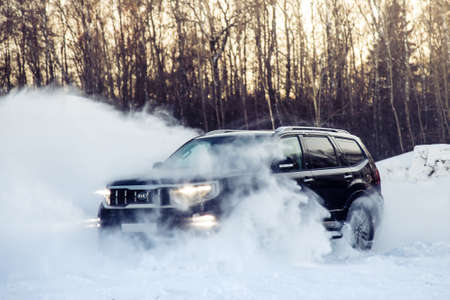Moscow, Russia - February 15, 2021: Kia Mohave 2021 black SUV parked in the forest in winter. General shot of the car from the front. Controlled skidding in snowdrifts.のeditorial素材
