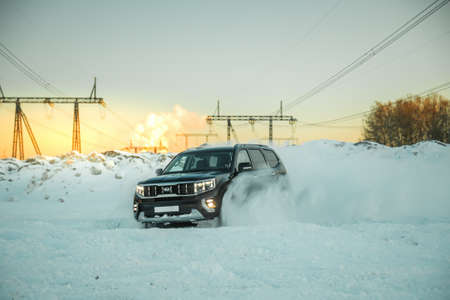 Moscow, Russia - February 15, 2021: Kia Mohave 2021 black SUV parked in the forest in winter. General shot of the car from the front. Controlled skidding in snowdrifts.のeditorial素材