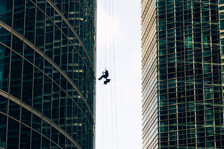 industrial mountaineering. Window cleaner performs work between two skyscrapers