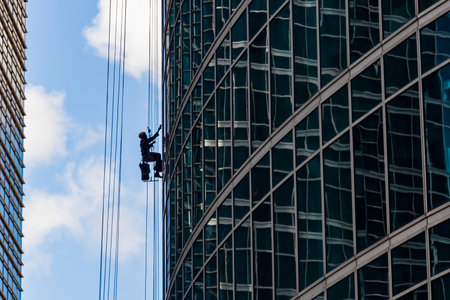 industrial mountaineering. Window cleaner performs work between two skyscrapers