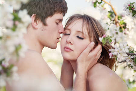 beautiful young couple kissing in the flowering gardensの写真素材