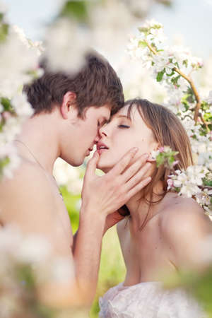 beautiful young couple kissing in the flowering gardensの写真素材