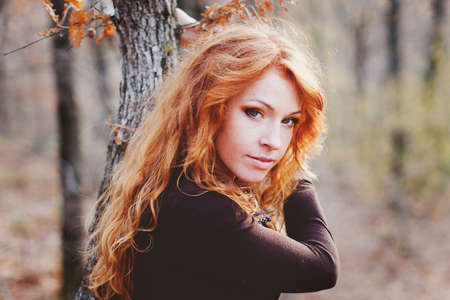 The red-haired girl in autumn leaves 
outdoor shot
の写真素材