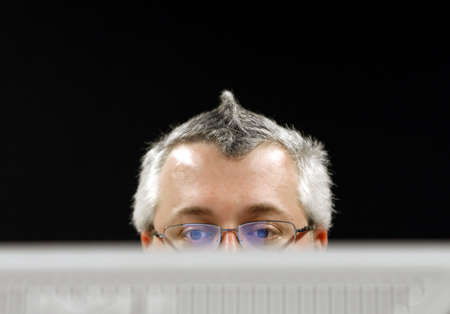 A man working behind a computer monitor.
