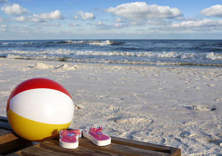 Beach ball and flip flops on a bench at the beach.の写真素材