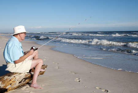 A senior man fishing from the beach at Perdido Key Florida.の写真素材