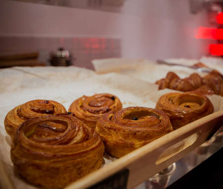 Bun with cinnamon and nuts lying on the wooden table in cafe, neon background.の写真素材