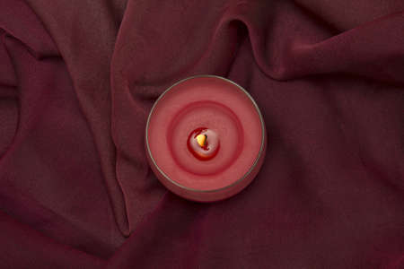 Lighted candle on red clothの写真素材