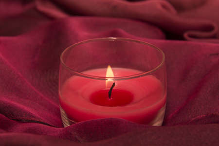 Lighted candle on red clothの写真素材