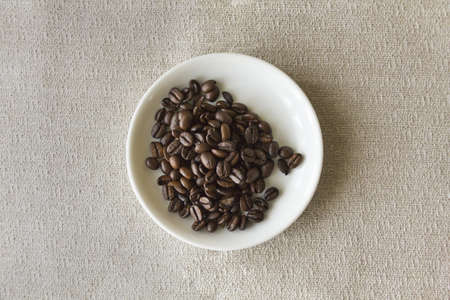 Fresh whole coffee beans inside of a small white saucerの写真素材