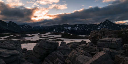 A stone valley on a mountain range in Canada in the evening with a beautiful sunset, a little covered with snowの写真素材