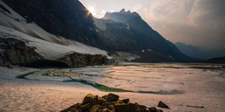 Ice and snow covered the lake at the foot of a mountain in Canada in the evening.の写真素材