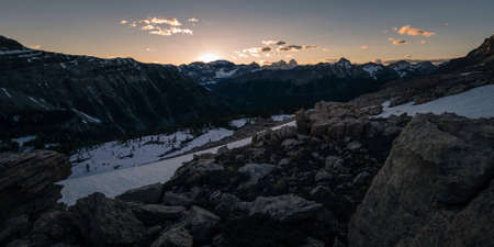 Snow-capped tops of wide, deserted mountains in Canada during the sunset with a beautiful skyの写真素材