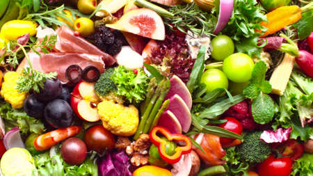 Many bright, fresh fruits and vegetables are laid out next to each other in one photoの写真素材