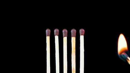Fire from lit matches and matches in a row on a black backgroundの写真素材