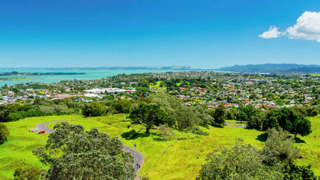 A view from afar of a small town on a sunny summer day near the sea, surrounded by many green plants