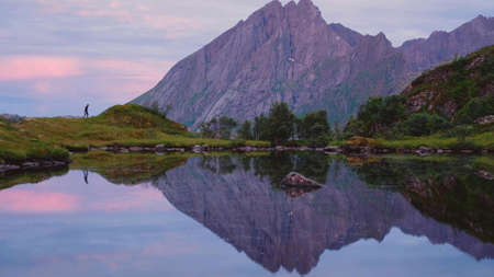 Side view of the reflection of mountains and sky in a lake at sunset in Norwayの写真素材