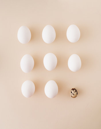 eggs arranged in a square. white eggs with one different quail egg with a dotted shell on a pastel background. minimal Easter concept.の写真素材