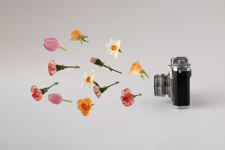 Retro camera with colorful spring flowers against white background. Creative concept. Minimal nature...
