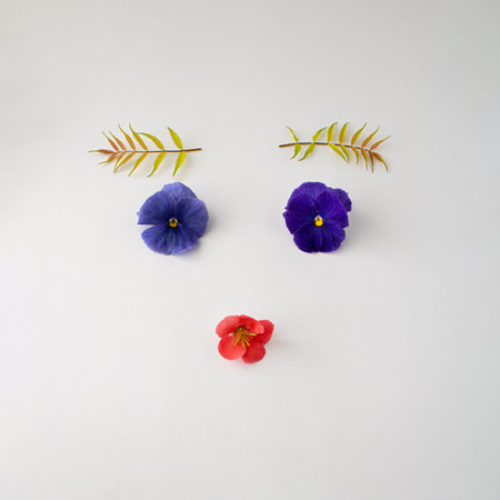 Face made with various flowers, violet, tropical flower, and leafs instead of eyebrows. Creative...