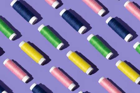 sewing thread in pink yellow, green and blue color . minimal pattern concept on purple background.の写真素材