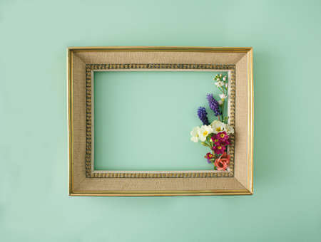 Vintage,retro and elegant golden picture frame , with colorful spring flowers. Minimal copyspace concept against pale green background.の写真素材