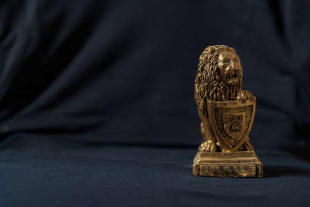 Statuette of a golden lion leaning on a shield. Black background.の写真素材
