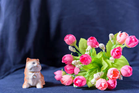 Sculpture lying cat with a collar with a diamond and rose bouquet on black background.の写真素材