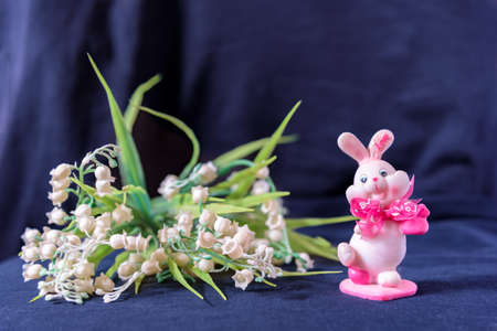 Valentines day pink bunny souvenir with lily of the valley on black background