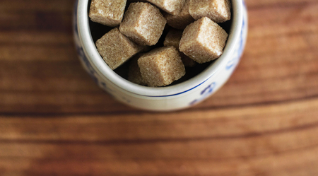 Photography with Kitchen Theme: Still Life with Brown Lump Sugar in Ceramic Bowl on Wooden Cutting Board.の写真素材