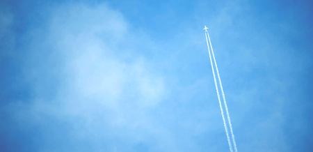 The White Plane Flying in the Sky and Letting Tracks in the Clouds.の写真素材
