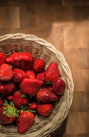 The Red Ripe Strawberries in Wicker Basket on Wooden Desk.の写真素材