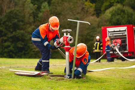 Germany, Niederstetten, Baden Wurttemberg. September 2019 Young firefighters in training, pumping...