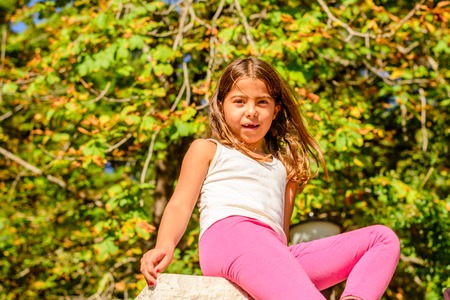 Seven year old girl is sitting on the wallの写真素材