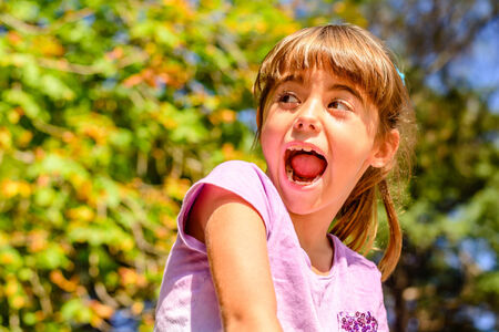 Seven year old girl is sitting on the wallの写真素材