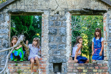 Four little girls playing around old house ruinsの写真素材