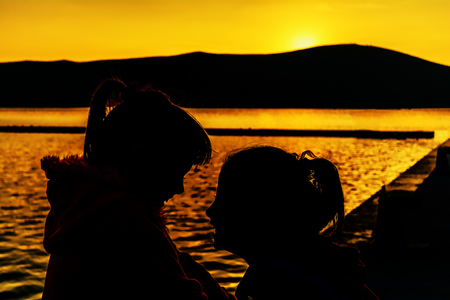 Two little girls are playing in the sunsetの写真素材