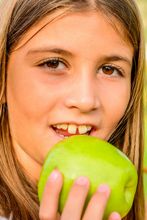 Beautiful nine year old girl is eating appleの写真素材