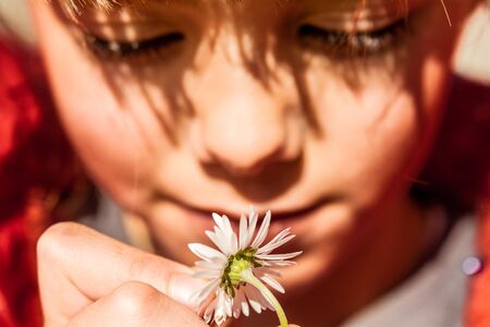 Beautiful little girl playing with flower. Focus on the flower.の写真素材